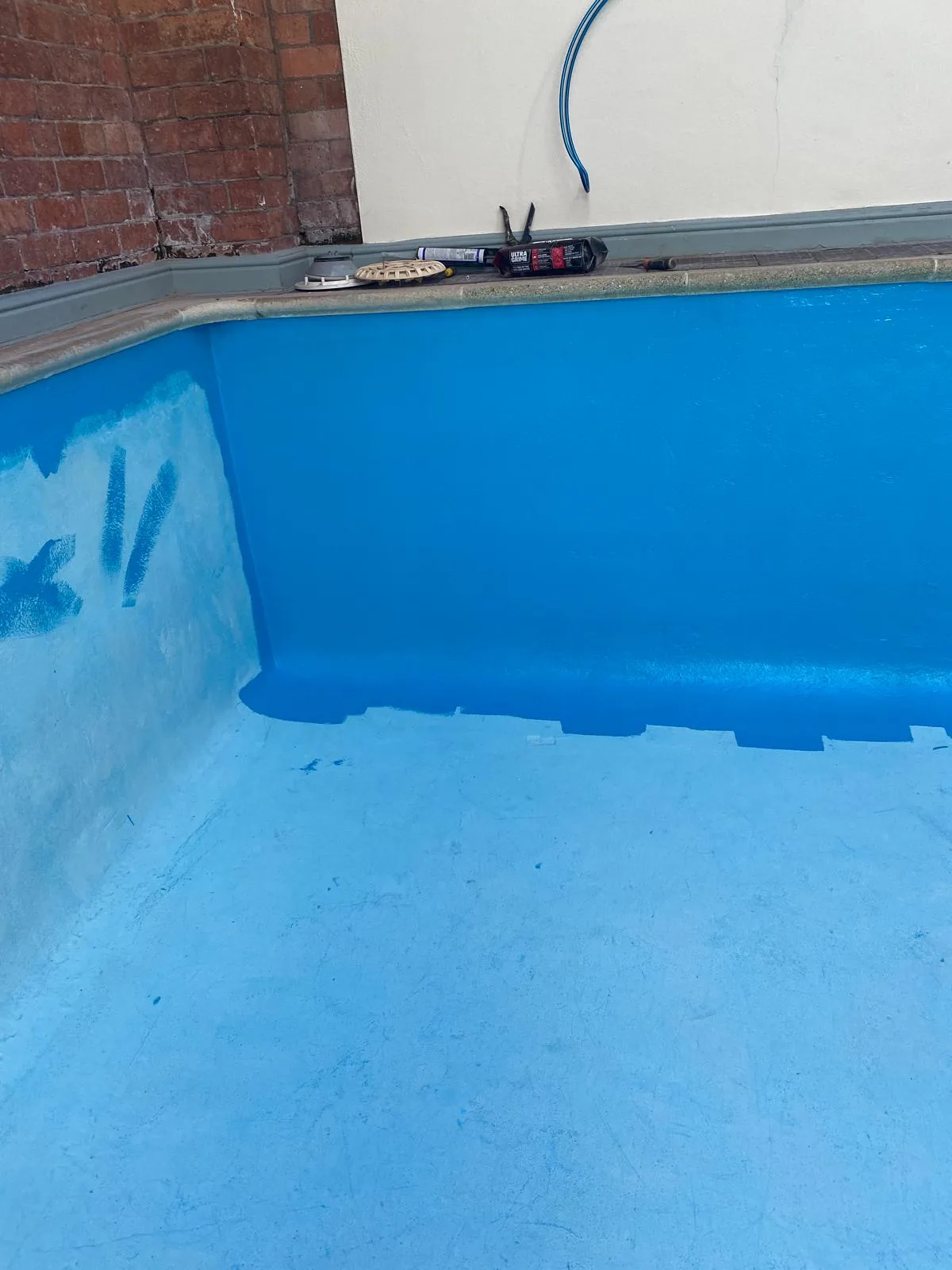 Indoor pool surface part-way through being coated in blue