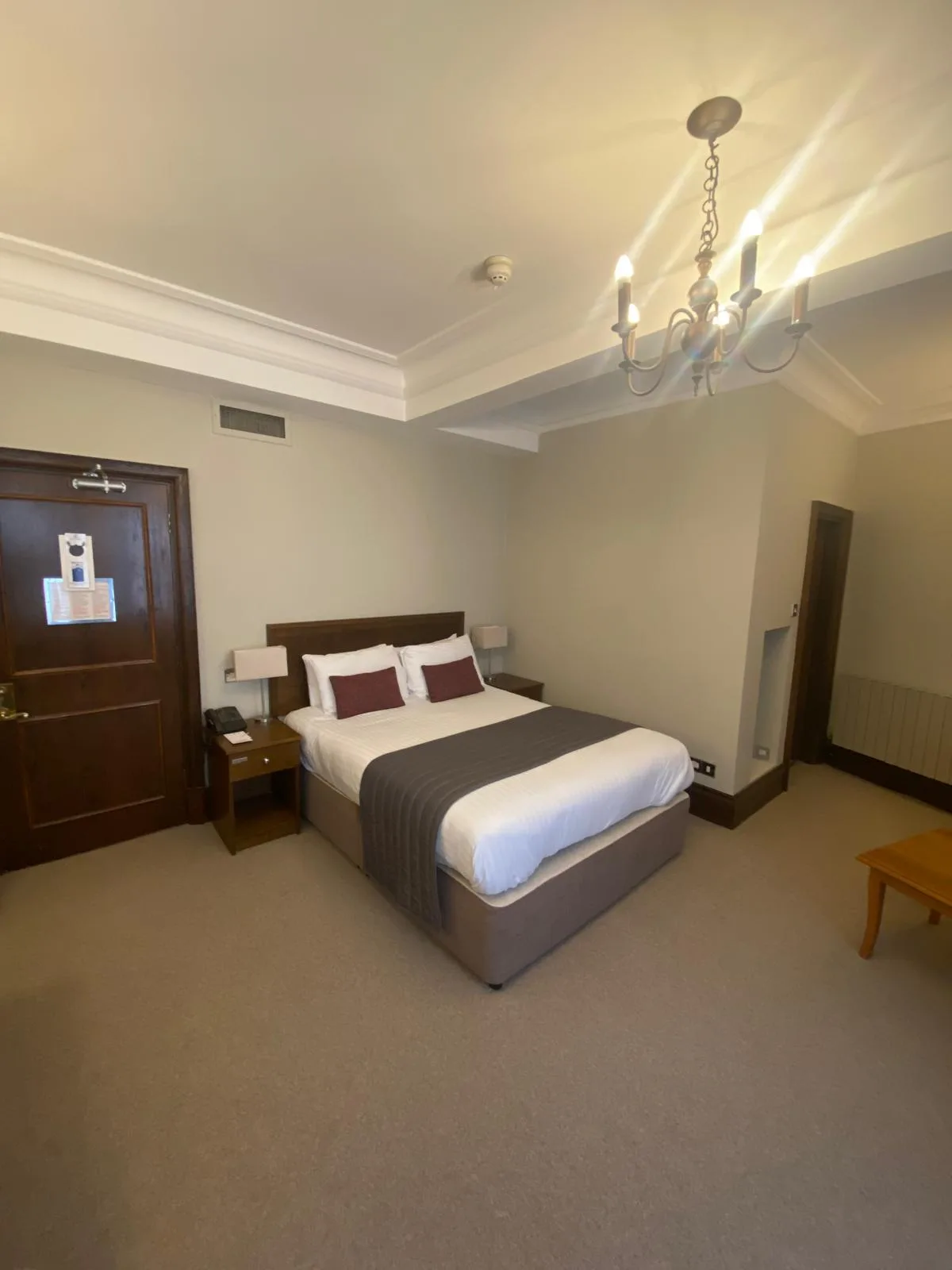 Hotel bedroom decorated by CH Supreme Decor with neutral walls, white ceiling and detailed cornice