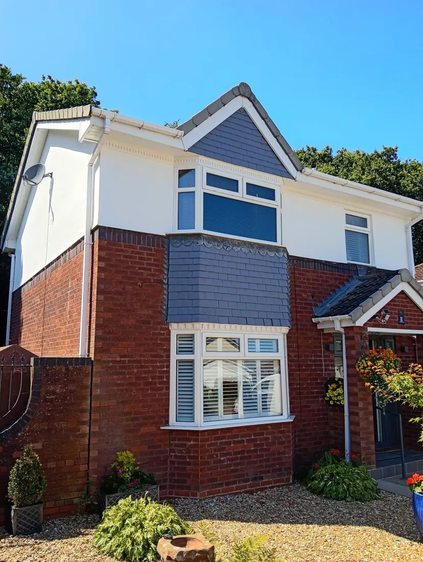 Two-storey house with freshly painted white upper walls and dark grey tiled features