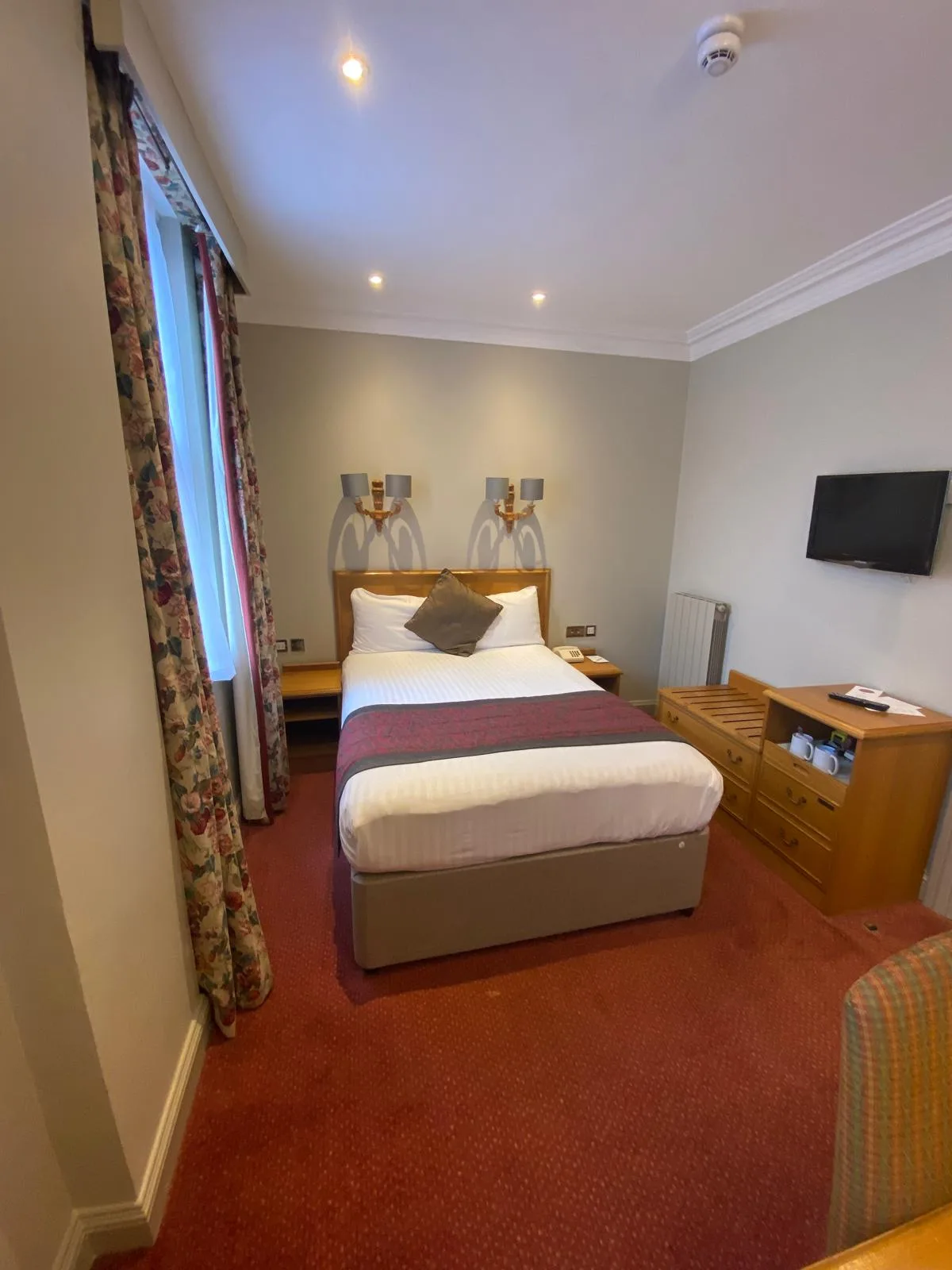 Hotel-style bedroom with neutral painted walls, white ceiling and cornice