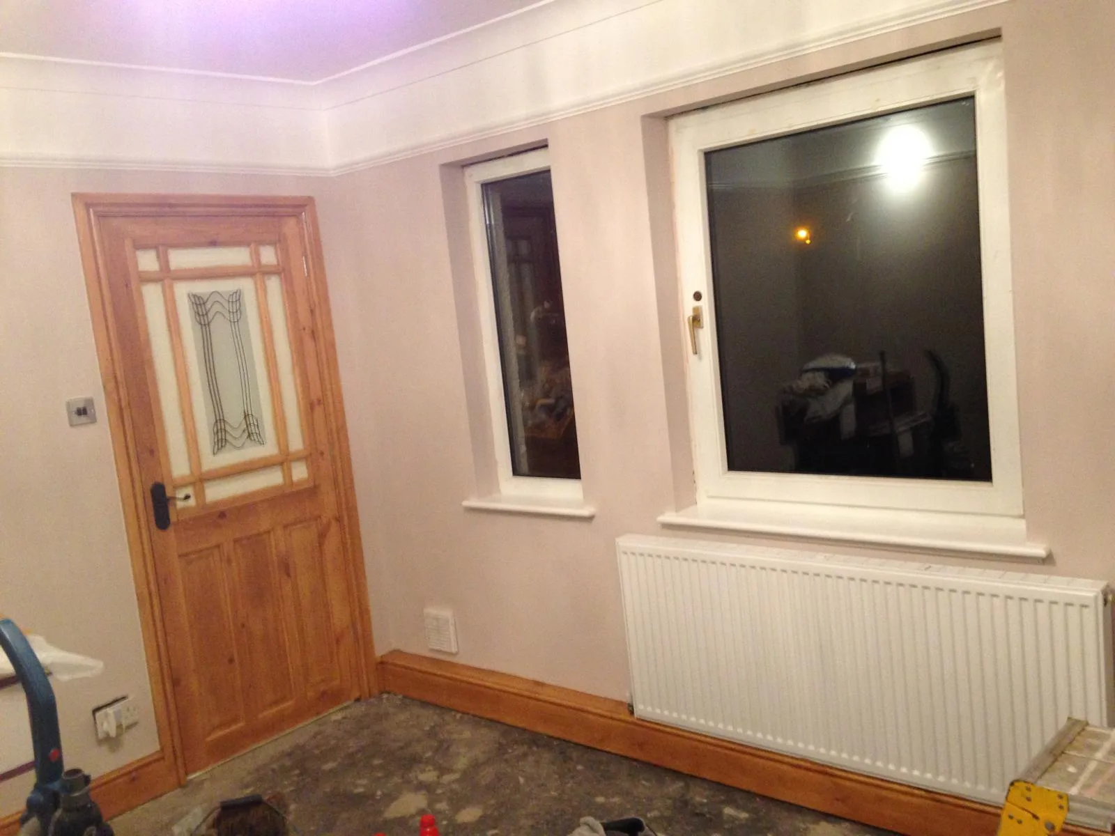 Room mid-decoration with painted walls, cornice and timber door, floor still bare